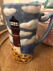 A tall mug with an ocean and lighthouse scene
