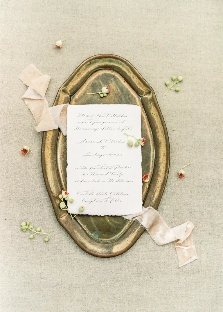 A vintage letter laying on a bronze tray with delicate ribbon