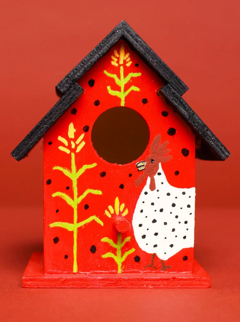 A red bird house with a painted hen