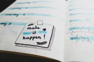 a planner with a sticky note which reads "make it happen"