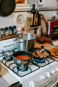 A white stove with three pots cooking food.