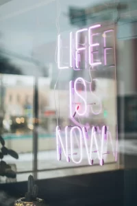 A neon sign which reads "LIFE IS NOW"