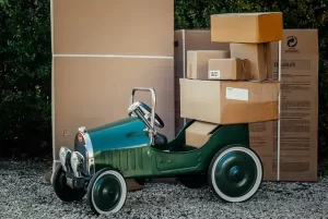 A vintage green, kids car with boxes piled on top. 