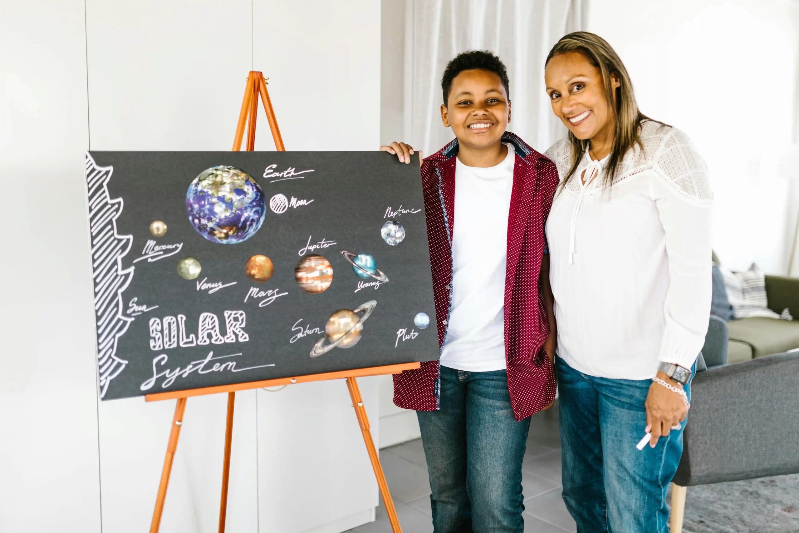 A mother with her preteen standing beside a solar system posterboard, representing the teach back facilitation homeschool technique