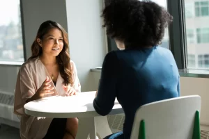 Two professional women sitting at a table, having a conversation
