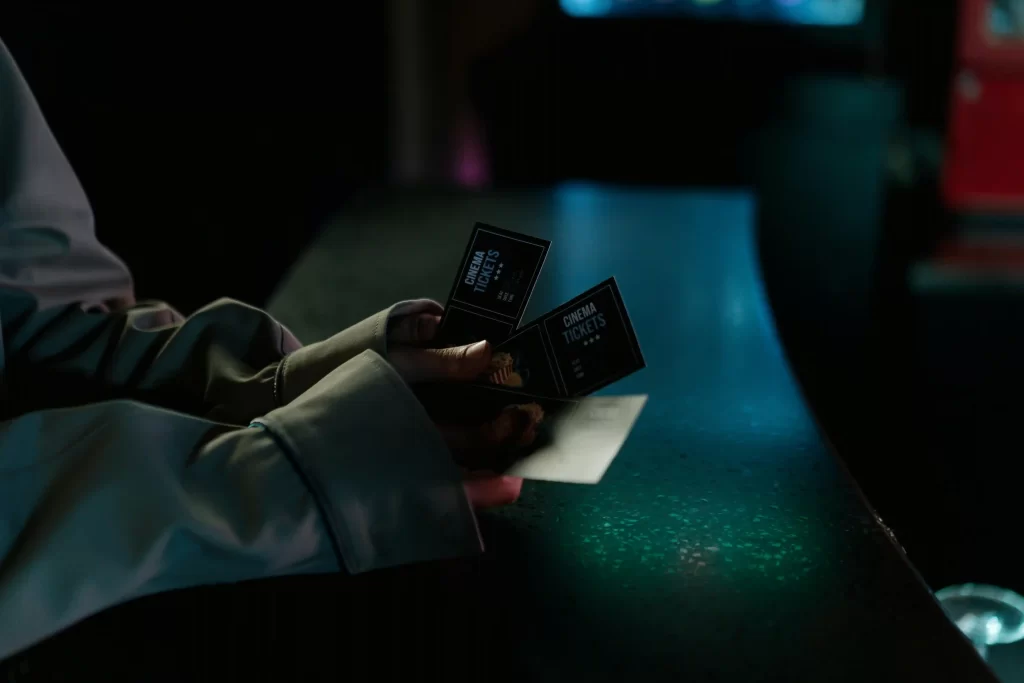 a woman's hands holding two movie tickets