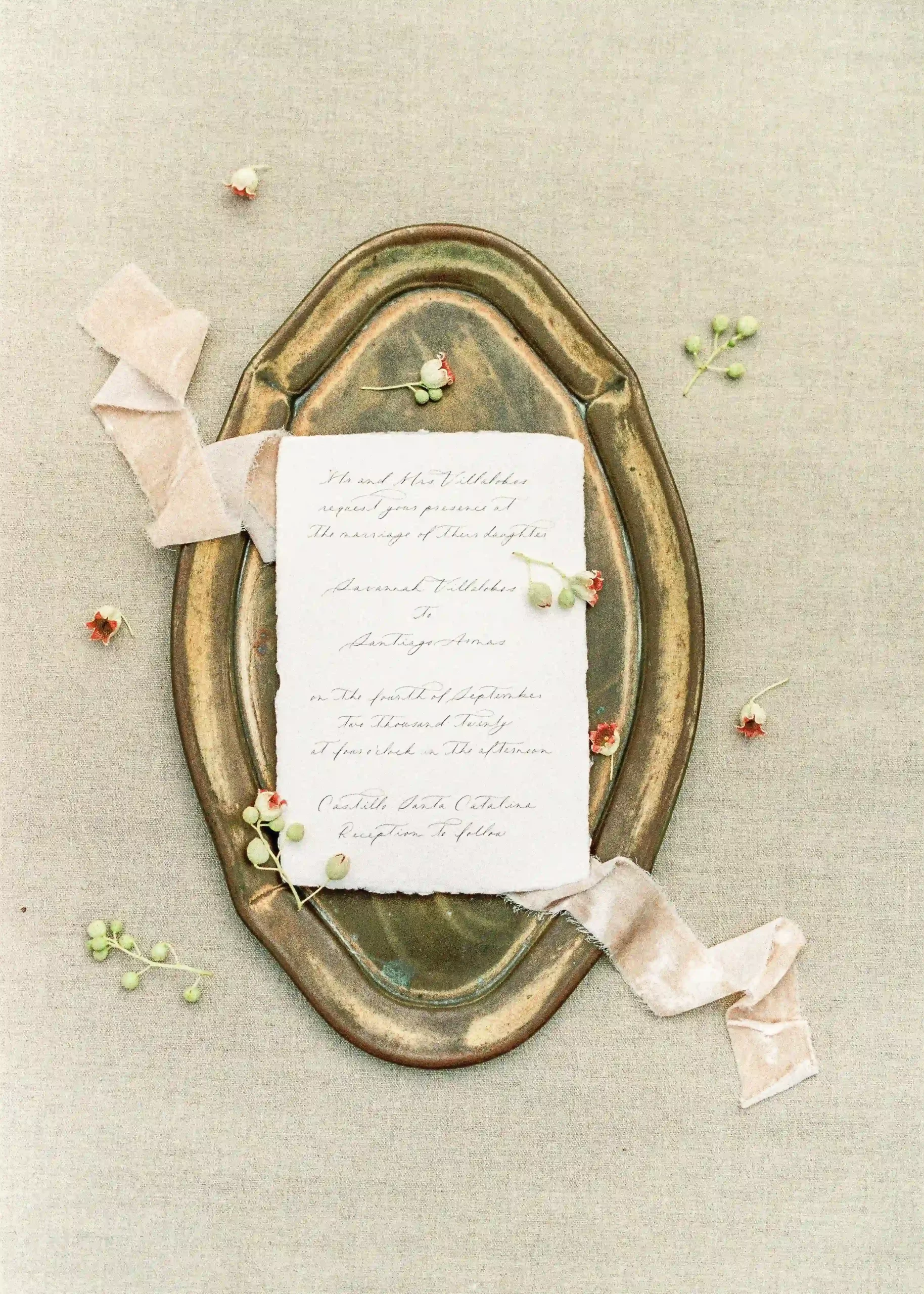 A vintage letter laying on a bronze tray with delicate ribbon