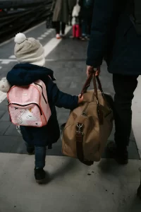 A glimpse from the back of an adult and child walking with bags