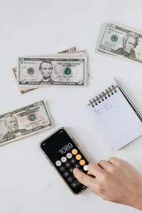 a calculator, paper money bills and a notepad sitting on a desk