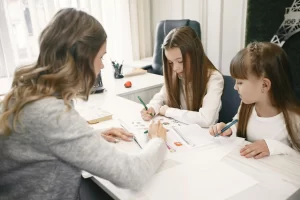 A mother homeschooling two young daughters, representing group learning
