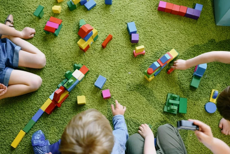 A few children playing with blocks on the ground.