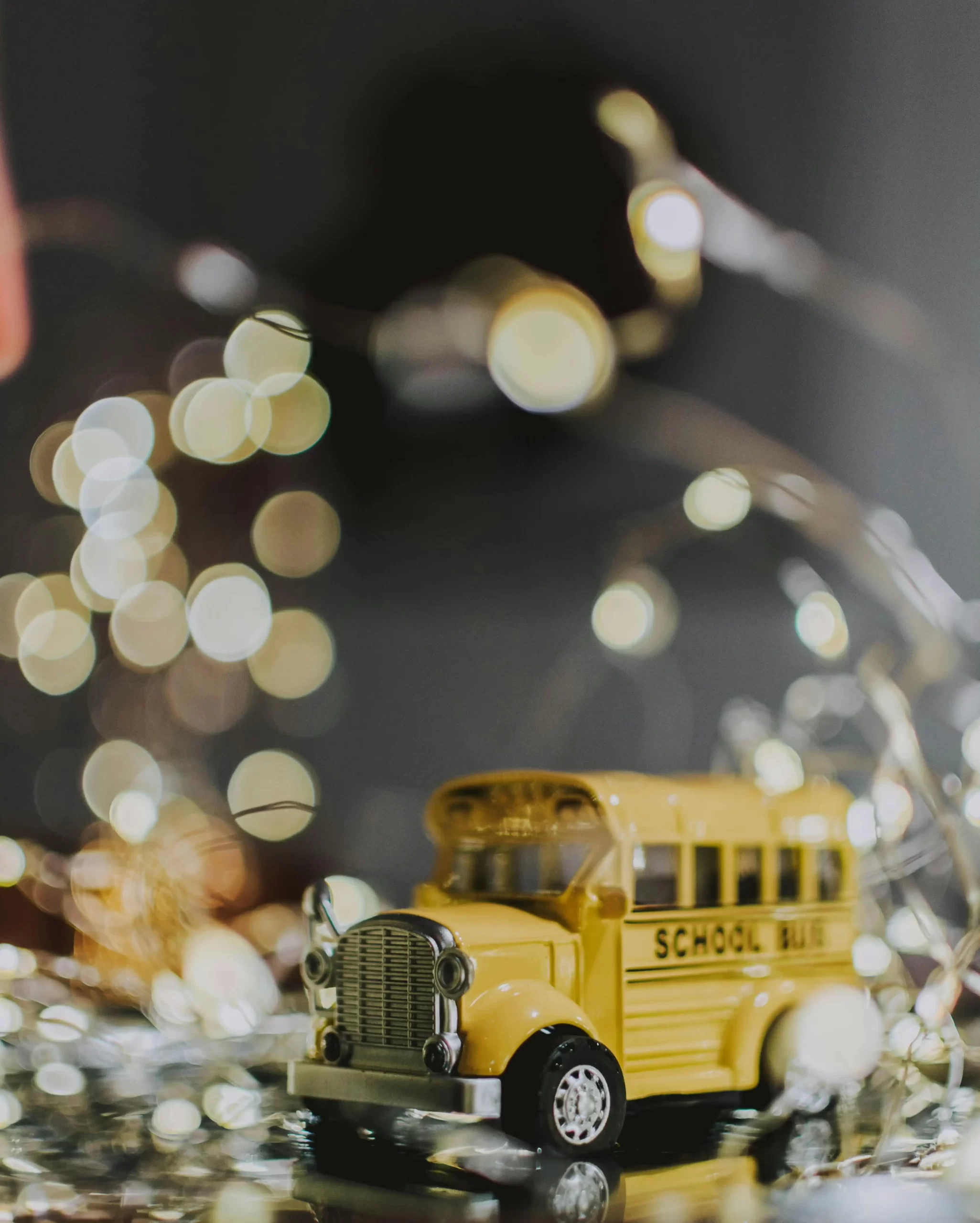 A small toy school bus with Christmas lights in the background, representing Christmas gift ideas for homeschooled children