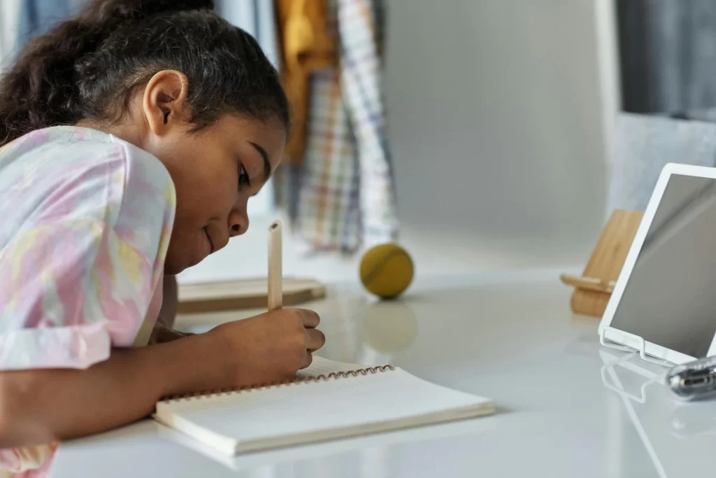 A young girl handwriting a letter, representing how to teach children the art of letter writing