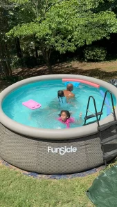 Three family members swimming in an outdoor pool, representing how to teach water safety at home