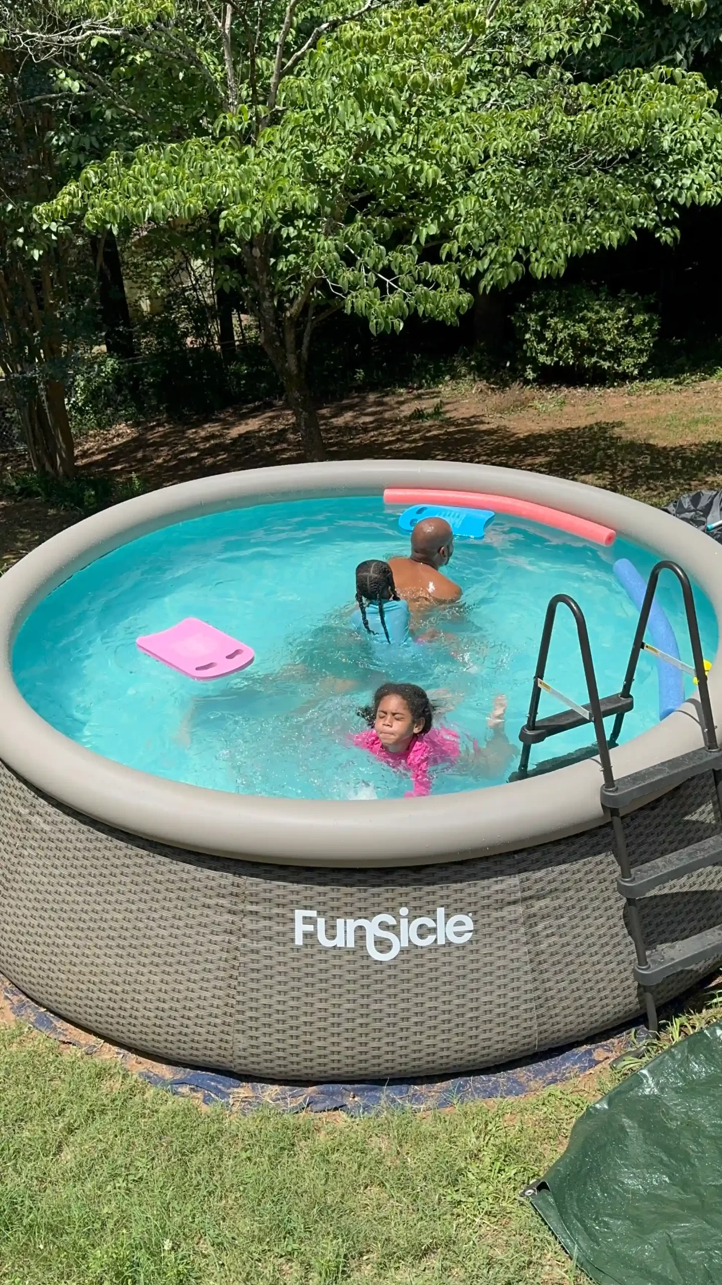 Three family members swimming in an outdoor pool, representing how to teach water safety at home